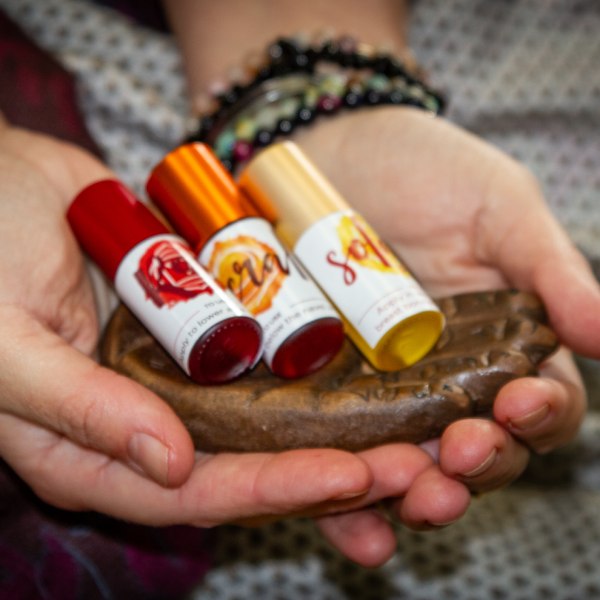 Essential oil blends for the chakras, held in therapists hands.