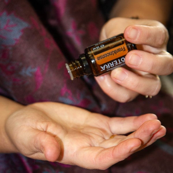 Massage therapist holding a bottle of dōTERRA Frankincense Essential Oil.