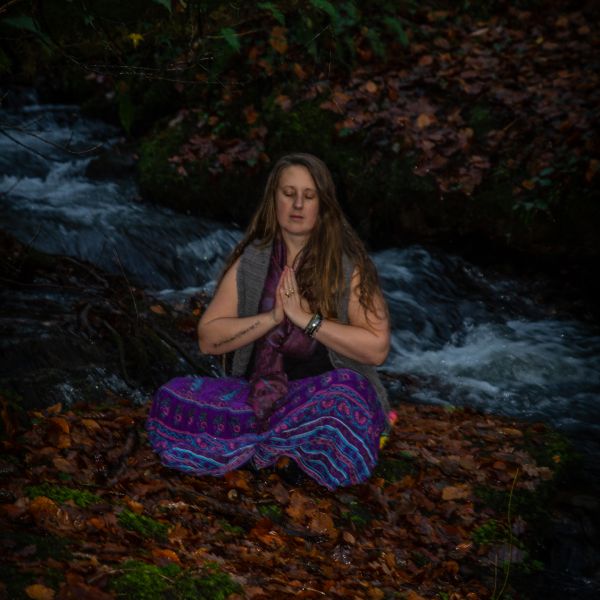 Energy healer sat meditating in nature.