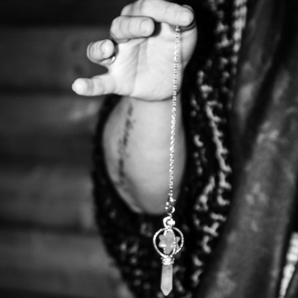 Therapist holding a pendulum between her finger and thumb.