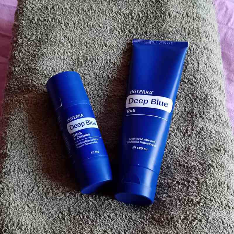 Deep Blue Rub and Deep Blue Stick resting on folded towels, used for natural muscle support at home